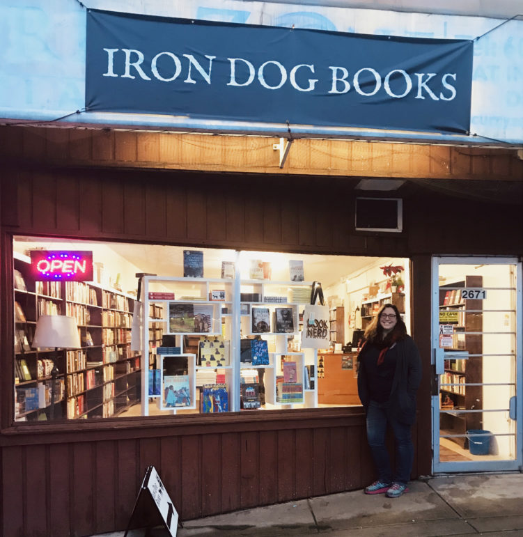 Bookseller Hilary Atleo poses in front of Iron Dog Books storefront