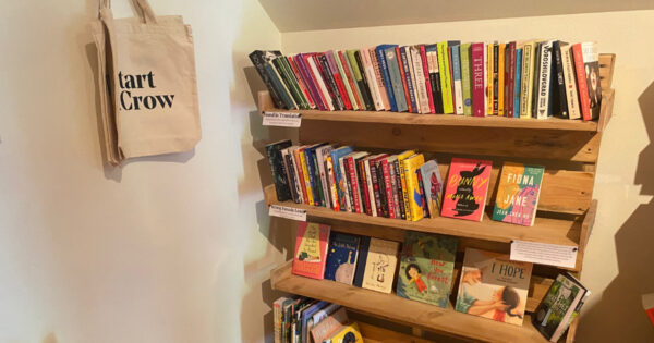 Bookshelf and tote bags reading Upstart & Crow