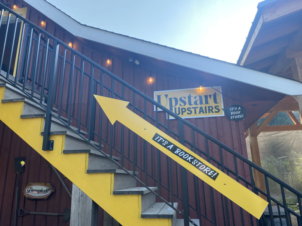 Photo of the yellow stairs up to the bookstore in a red barn.